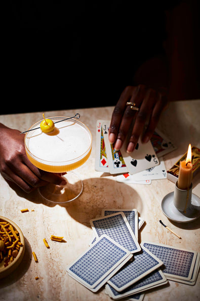  A hand lifting a Cide-Car coupe over a card table lit by candles 