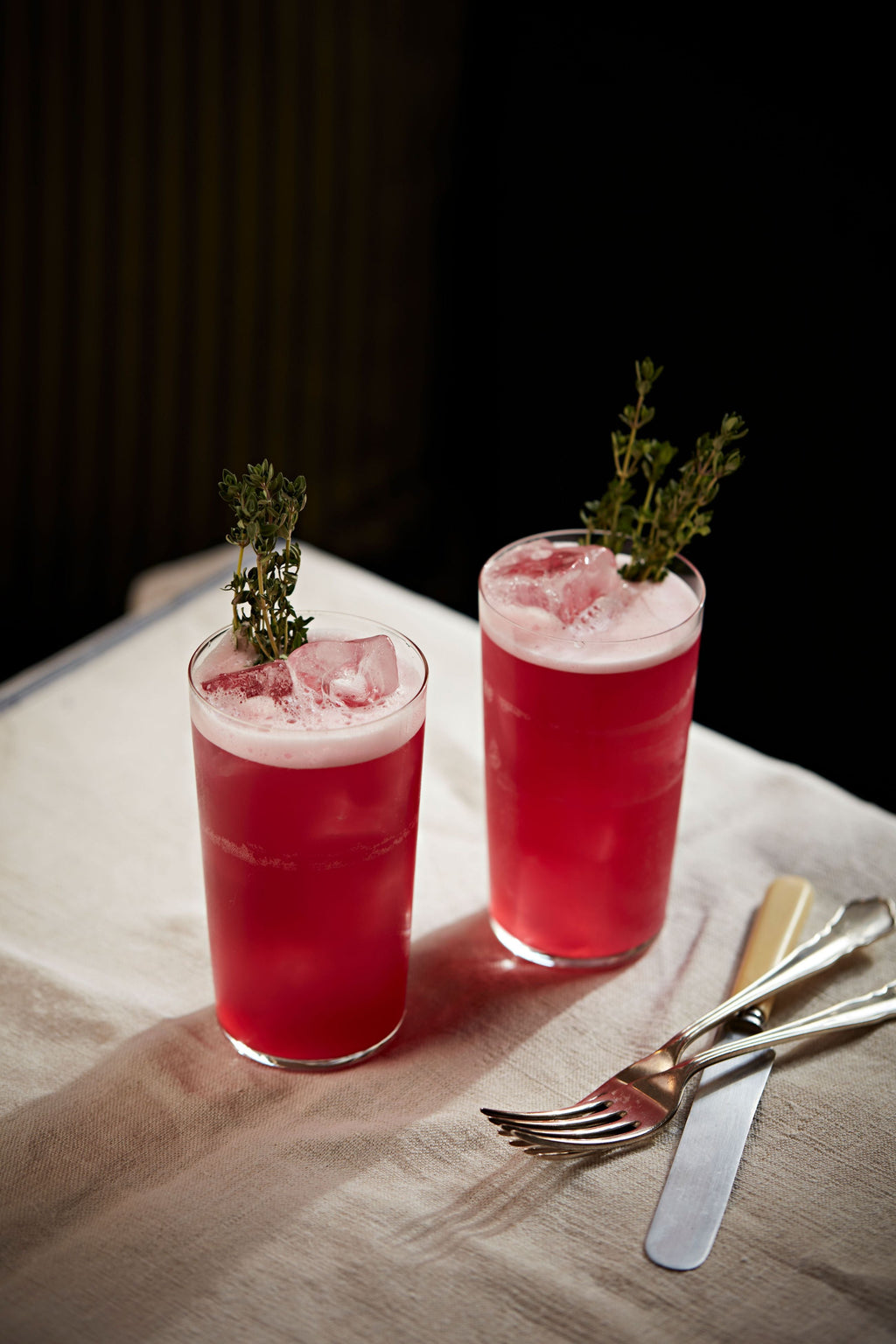 Two deep red Every Star highballs garnished with sprigs of thyme