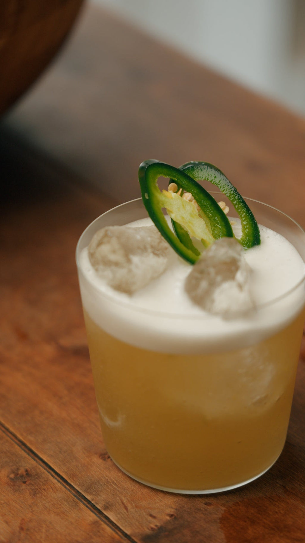 A foamed Botivo Picante in a tumbler topped with jalapeno slices
