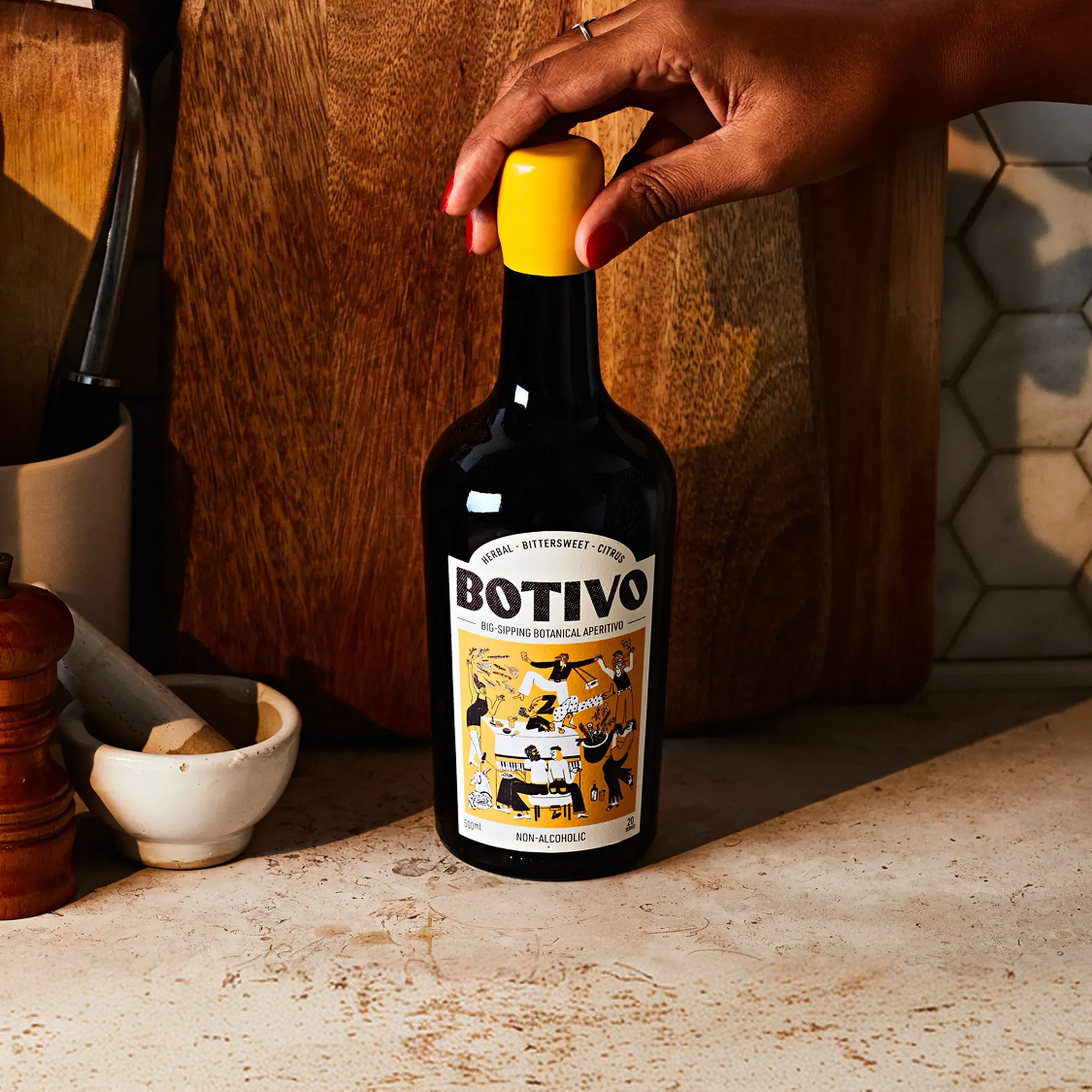 Hand placing a Botivo bottle on a kitchen worktop
