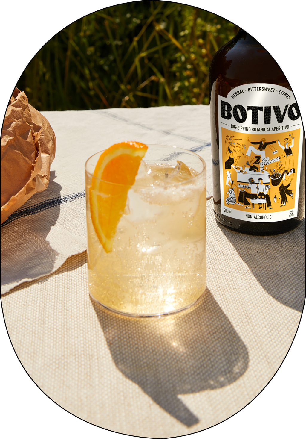  Glass of Botivo on ice with an orange slice next to a Botivo bottle in the sunshine 